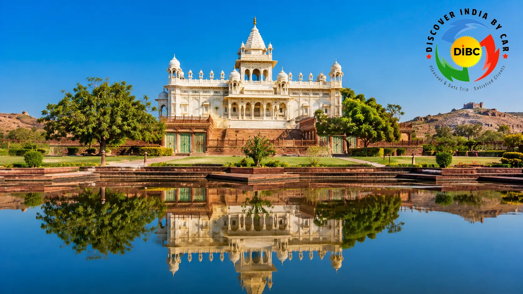 The white marble cenotaph of Jaswant Thada glowing translucent under bright sunlight with manicured gardens and lake in Jodhpur