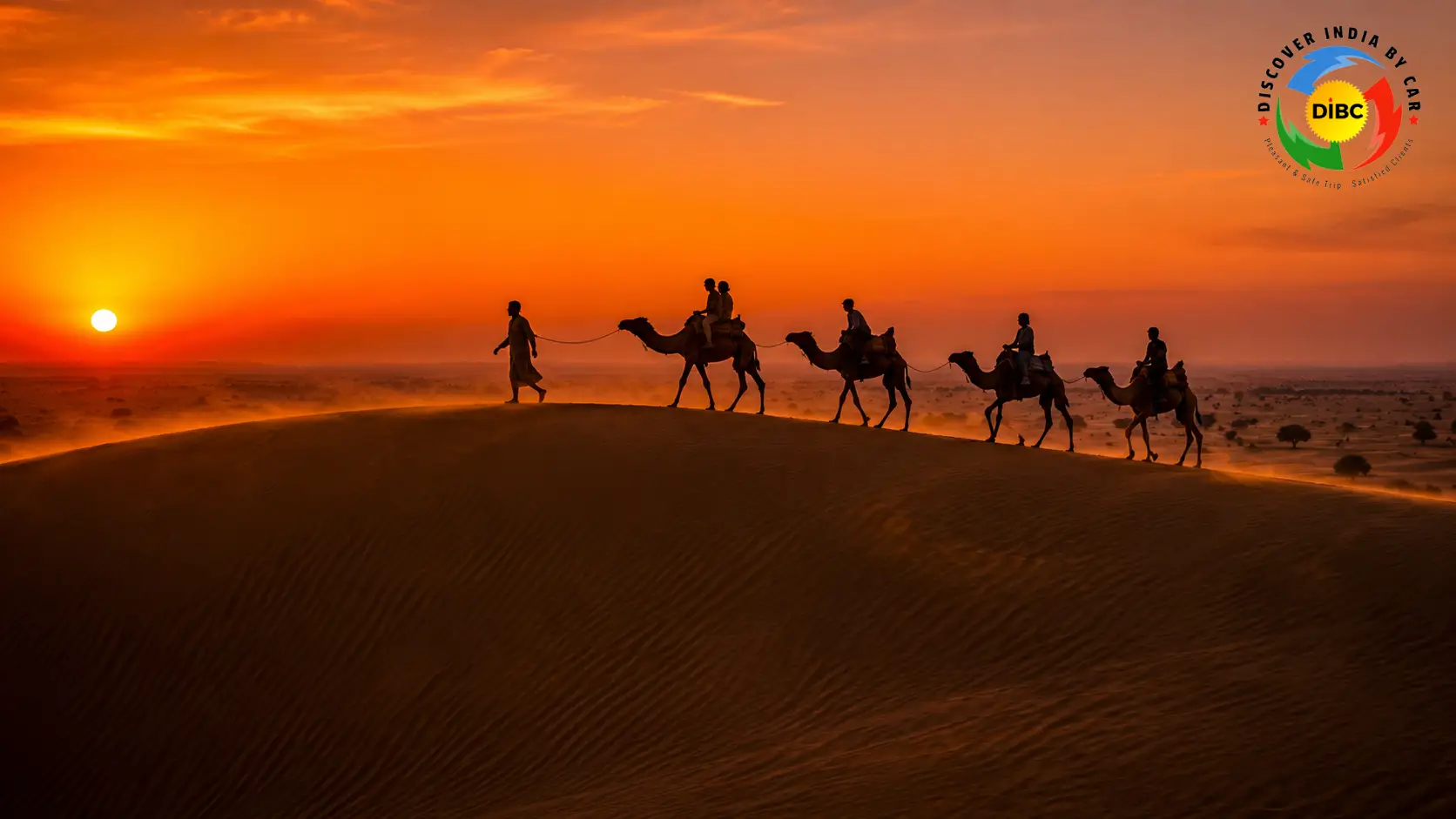 A camel caravan walking across the ridges of Sam Sand Dunes in the Thar Desert during a dramatic orange sunset